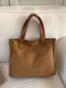 Sac fourre-tout en daim marron avec double poignée et logo embossé sur canapé blanc