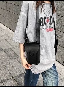 Minimalist black PU leather crossbody phone bag shown on a model in an outdoor street setting