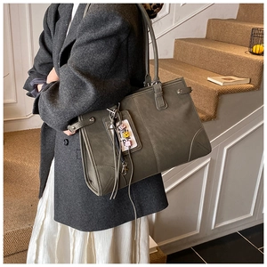 Detail view of large olive green tote bag featuring decorative metal buckle and contrast stitching
