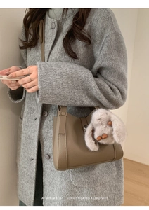 Close-up of retro khaki leather handbag with litchi texture and cute rabbit pendant