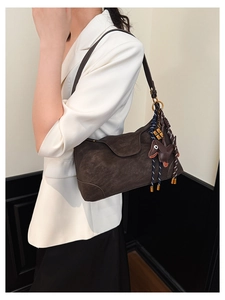 Deep brown matte leather shoulder bag with a cute dog pendant worn with a white blazer