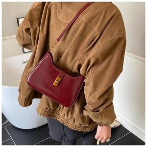 Detail of dark red faux leather shoulder bag featuring a golden rectangular twist lock