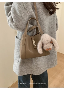 Detail of dark brown pebble leather tote bag with a cute plush bunny charm accessory