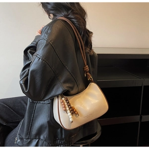 Detail of minimalist cream leather hobo bag with dark brown knot handle and colorful bead charm