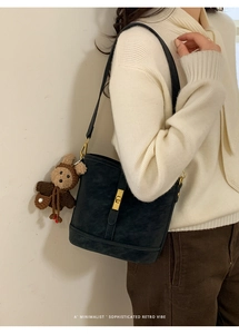 Détail du sac seau noir mat rétro avec boucle dorée et pendentif ourson mignon