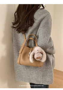 Detail of camel lychee leather tote bag with silver twist lock and cute bunny pendant