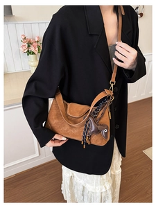 Brown suede crossbody bag detail featuring a decorative braided rope and leather horse charm