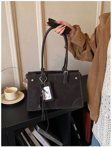 Detail of dark brown matte tote bag showing long handles and silver buckle accents