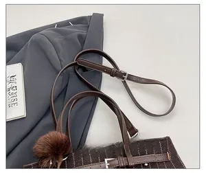 Detail of adjustable brown leather strap and textured striped fabric with fuzzy charm