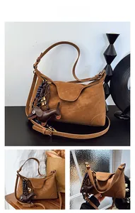Detail of caramel suede handbag with dachshund charm and woven blue rope accent