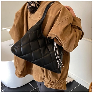 Detail of black quilted hobo bag worn by model, showing size and soft texture