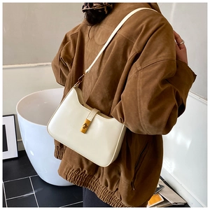 Close-up of cream faux leather shoulder bag featuring a sleek gold rectangular clasp