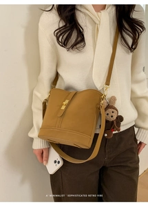 Détail du sac seau rétro jaune gingembre avec fermoir doré et breloque en tricot