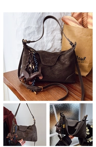 Detail of dark brown retro textured shoulder bag with dachshund charm and flap closure