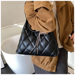 Detail of black quilted leather hobo bag with tassel showing texture and size on shoulder