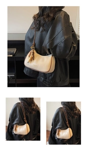 Detail of cream hobo bag with contrast brown strap and wooden bead charm accessory