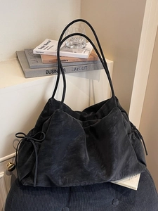 Minimalist black matte leather tote bag with drawstring side details and slim shoulder straps