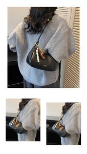 Detail of black matte leather crescent bag with colorful wooden bead charm and text