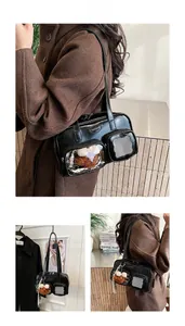 Détail du sac Boston en cuir verni noir avec poche transparente et breloque ours mignon