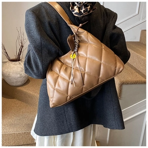 Macro view of brown quilted hobo bag with braided metal chain and yellow smiley badge