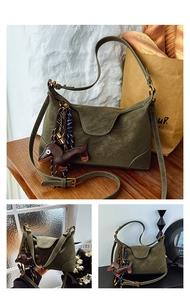 Detail of dark green suede shoulder bag with brown dachshund charm and woven rope accessory