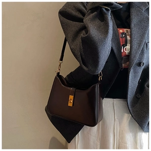 Detail of dark brown leather hobo bag featuring a gold metal twist lock and square clasp