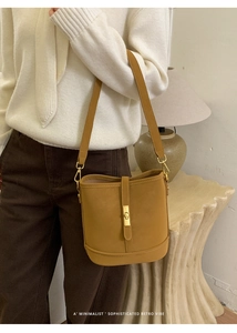 Détail d'un sac seau en cuir jaune moutarde avec élégant fermoir rectangulaire doré