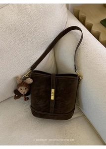 Détail d'un sac seau marron foncé avec fermoir doré et un petit pendentif ours brun