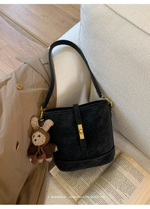 Détail du sac seau rétro en cuir noir avec serrure dorée et breloque ours en peluche