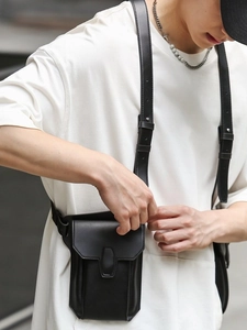 Minimalist black PU leather travel bag with adjustable strap shown on model outdoors
