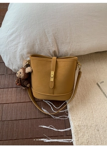 Détail du sac seau en cuir jaune gingembre avec fermoir doré et breloque ours