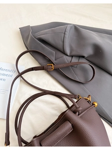 Detail of dark brown lychee pattern leather bucket bag with gold hardware buckle