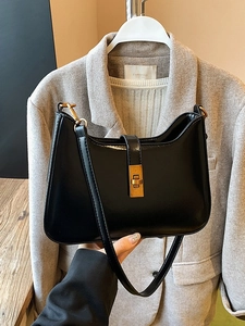 Minimalist black glossy underarm bag with gold metal buckle and leather shoulder strap