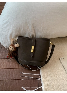 Détail du sac seau rétro marron foncé avec fermoir doré et breloque ours en tricot