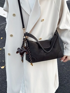 Dark brown matte Hobo shoulder bag with dachshund charm and striped tassels in outdoor setting