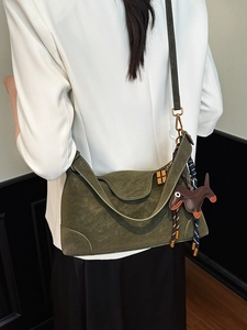 Dark green suede crossbody bag for women with gold clasp and dog charm worn by model