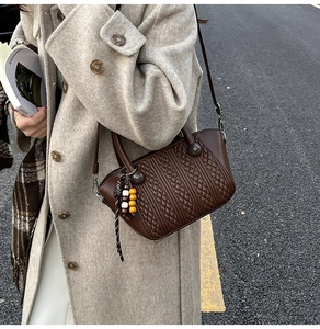 Detail of vintage brown woven leather bucket bag with wooden bead charm and thin strap