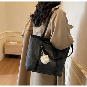 Detail of grey textured tote bag with a white plush lamb charm and gold logo detail