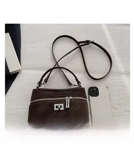 Détail de sac rétro marron foncé avec boucles argentées sur fond de tissu blanc