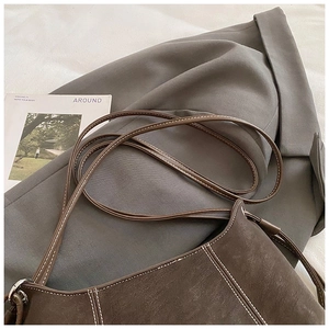 Detailed view of dark brown crossbody bag with contrast white stitching and matte finish
