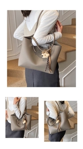 Detail of grey lychee pattern tote bag with shoulder strap and a cute plush bear charm