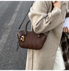 Detail of coffee brown woven bucket bag with wood bead tassel and quilted leather texture
