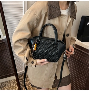 Detail of vintage black woven pattern bucket bag with decorative wooden beads and PU leather texture