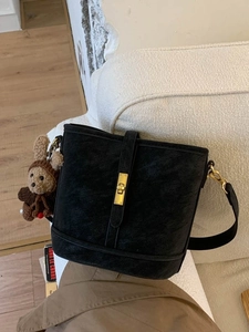 Sac seau noir rétro avec breloque ours en peluche sur fond de canapé texturé blanc