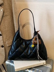 Black quilted hobo bag with charms on a silver suitcase for winter casual commute style