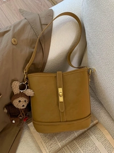 Sac seau vintage jaune moutarde avec fermoir doré et charme d'ours sur un canapé