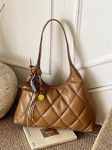 Brown quilted leather shoulder bag with diamond stitching and cute charms on a desk