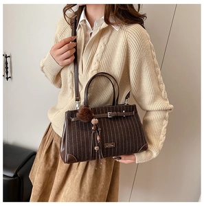 Detail of a brown suede striped handbag paired with a beige knit sweater for a cozy look