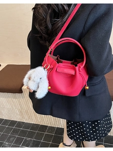 Red pebbled leather bucket bag featuring a cute white bunny charm and adjustable strap