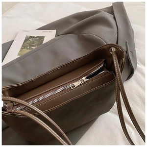 Detailed close-up of dark brown leather tote bag with silver zipper and white stitching